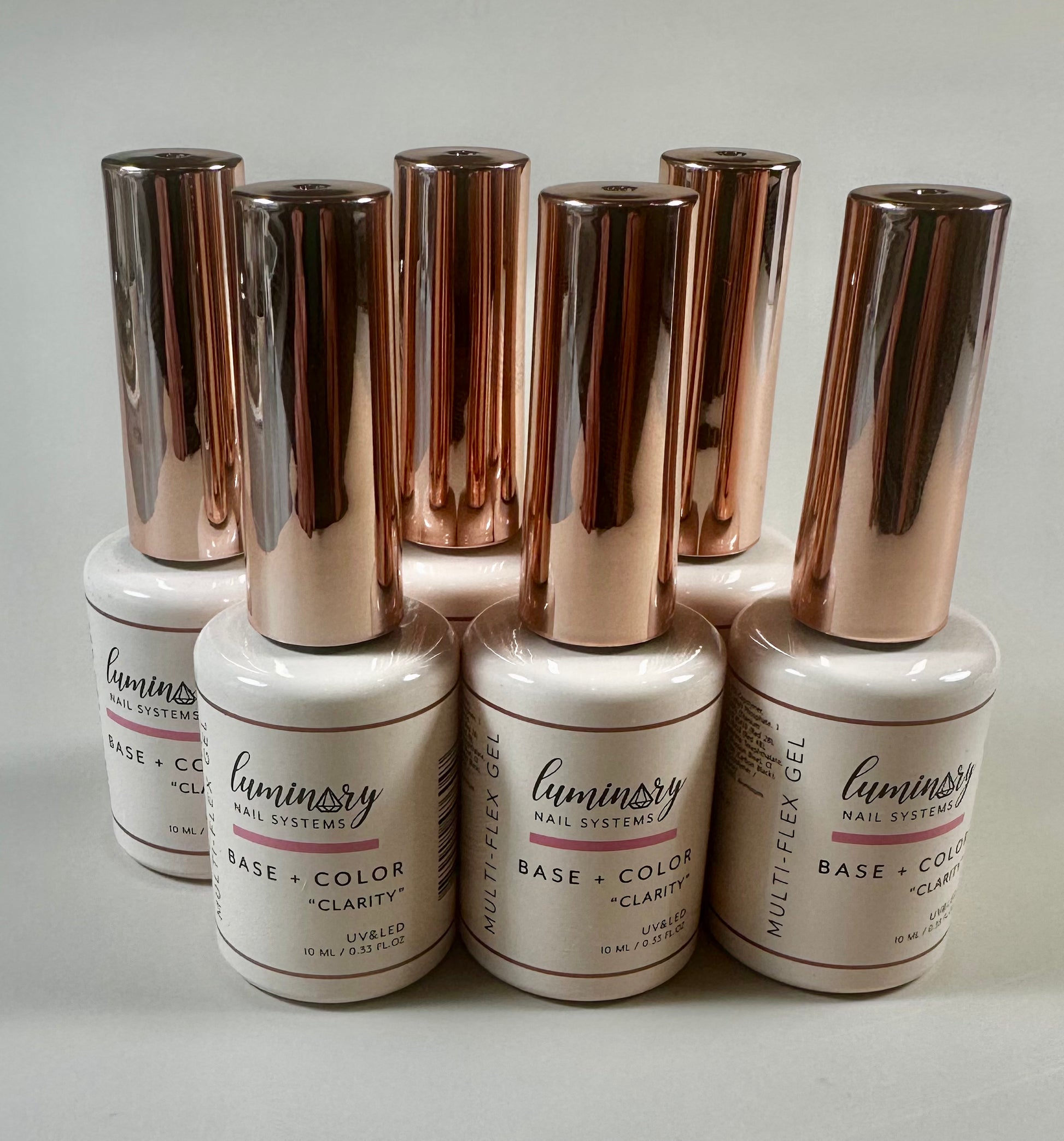 Set of Luminary nail gel polish bottles with rose gold caps on a white background